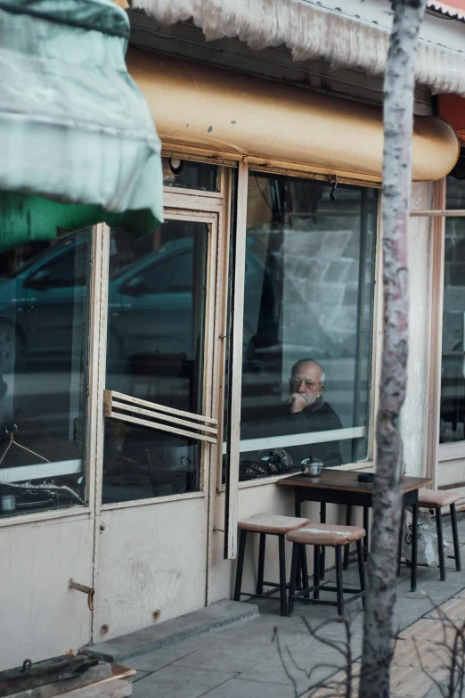 an old man is sitting outside of a restaurant