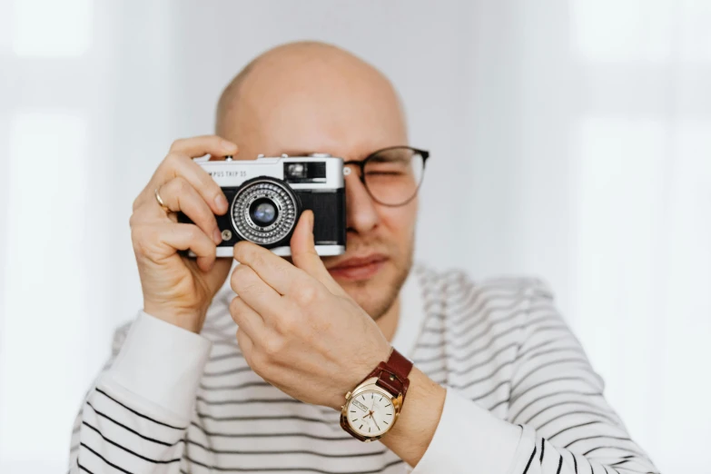 a man taking a picture with a camera, by Adam Marczyński, pexels contest winner, photorealism, wearing square glasses, dieter rams, watch photo, avatar image