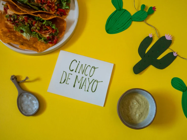 a plate of food next to a sign that says cinco de mayo, pexels contest winner, on a yellow paper, pair of keycards on table, studio product shot, mayonnaise