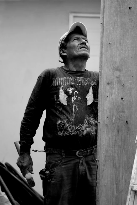 a black and white photo of a man holding an umbrella, inspired by Ángel Botello, street art, holding wood saw, standing on a ladder, indigenous man, wearing a tee shirt and combats