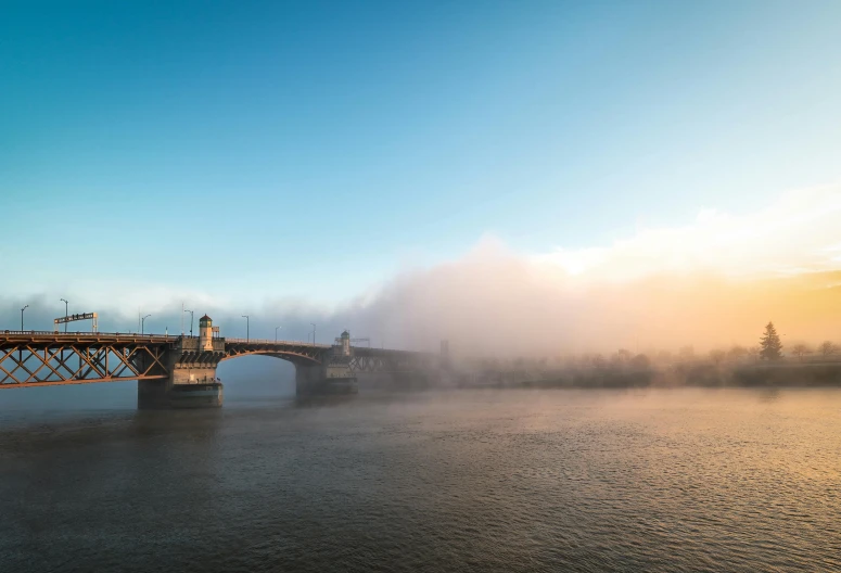 a bridge over a body of water on a foggy day, by Sebastian Spreng, pexels contest winner, thames river, steam clouds, 8k hdr morning light, hazy