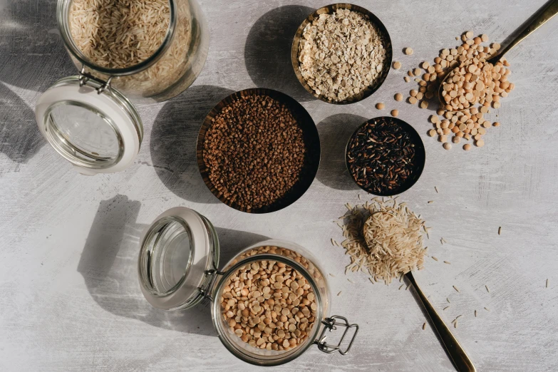 a table topped with lots of different types of cereal, by Nina Hamnett, trending on pexels, renaissance, mineral grains, brown, jars, rice