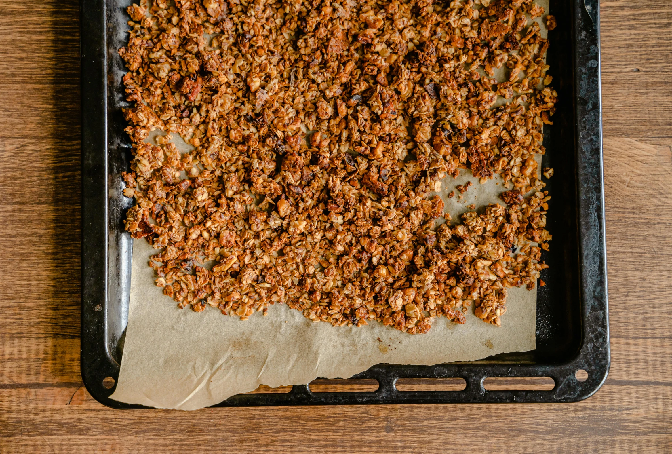 a pan filled with granola sitting on top of a wooden table, by Helen Stevenson, parchment paper, thumbnail, square, slate