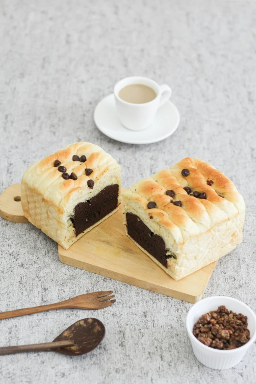 a couple of pastries sitting on top of a wooden cutting board, mingei, white with chocolate brown spots, daopao, official product image, with bread in the slots