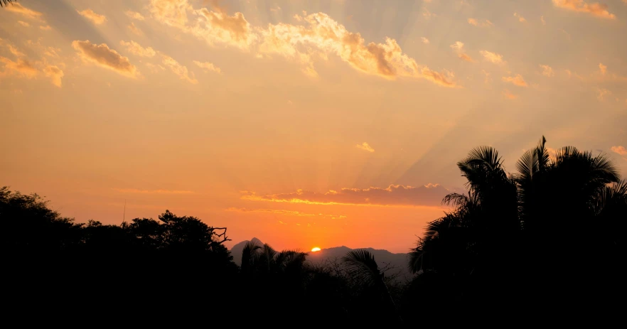 the sun is setting behind the clouds in the sky, by Peter Churcher, pexels contest winner, romanticism, tropical atmosphere, sunset in a valley, rays of shimmering light, pastel orange sunset