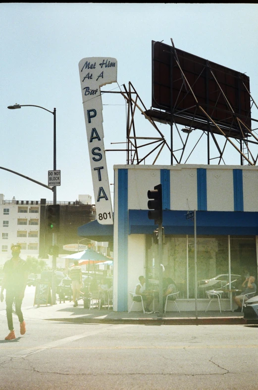 a person crossing the street in front of a fast food restaurant, a photo, by William Berra, blue slide park, pasta, with the sun shining on it, hollywood scene