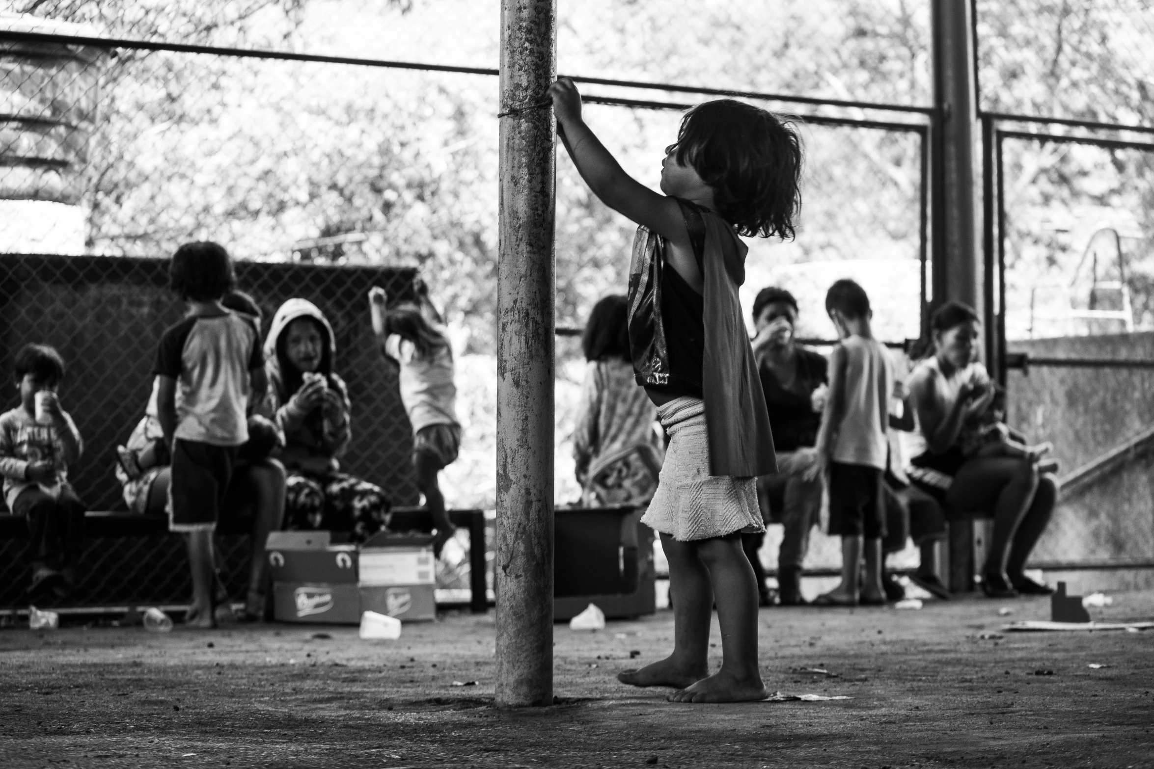 a little girl standing on top of a wooden pole, a black and white photo, by Nadir Afonso, process art, people dancing in background, thailand, resting after a hard fight, playground