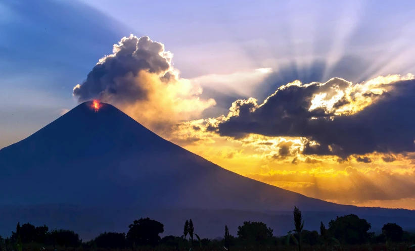 a sunset seen behind a very majestic peak of mist