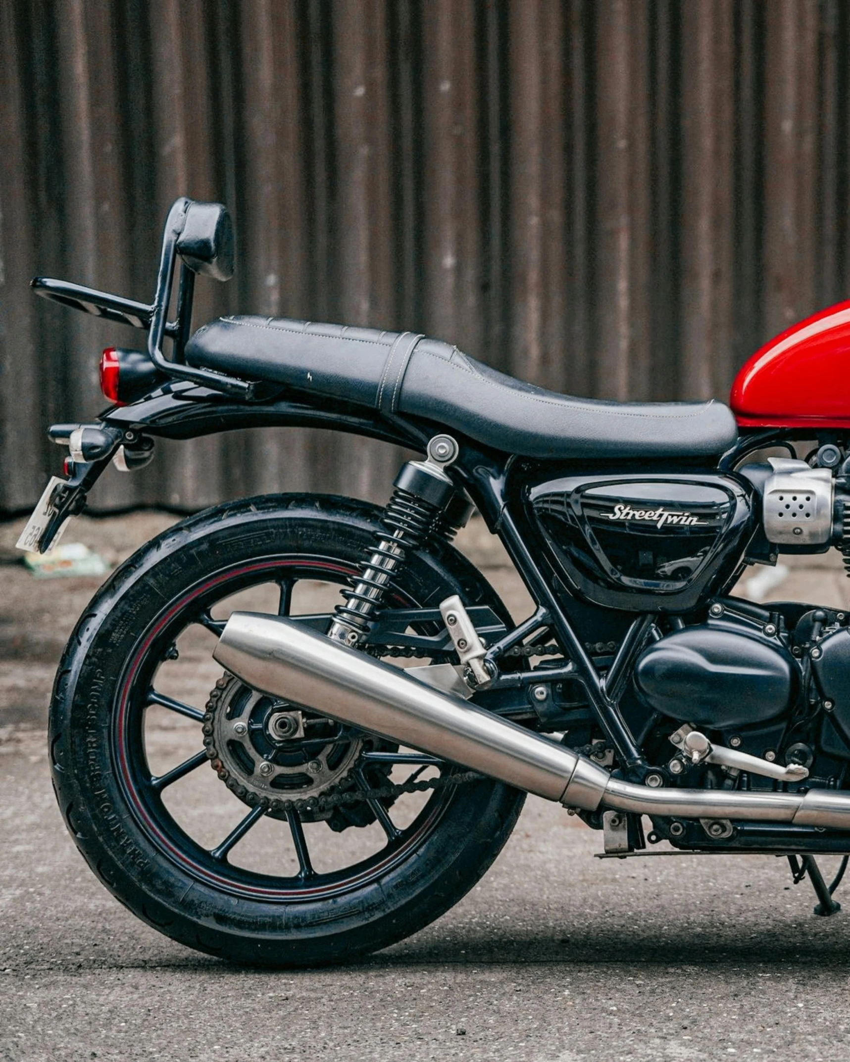 a red motorcycle parked in front of a building, triumph, red and black details, turned back to camera, detailed product image