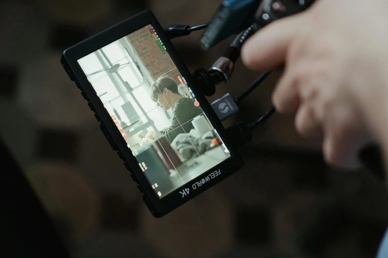 a close up of a person holding a camera, large screen, close to the camera