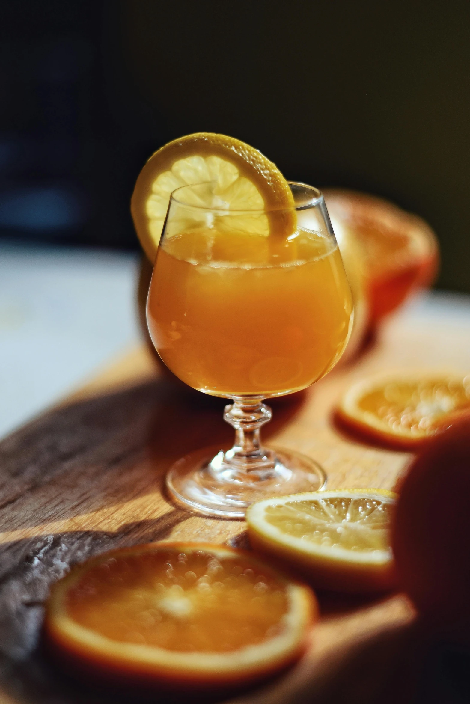 a glass of orange juice sitting on top of a cutting board, drinks bourbon, kailee mandel, yet unrecognizable, orange slices