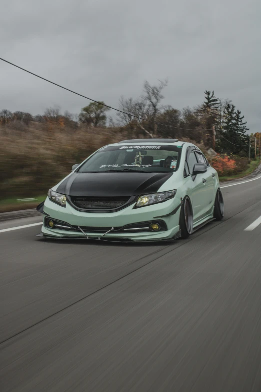 a green honda civic on the road during autumn