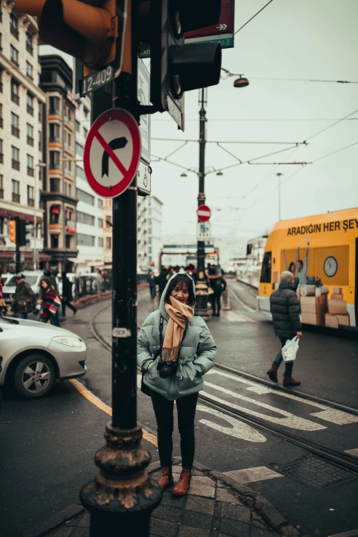 a woman standing next to a traffic light on a city street, a picture, by Niko Henrichon, trending on unsplash, trams, square, girl wearing hoodie, lots of signs