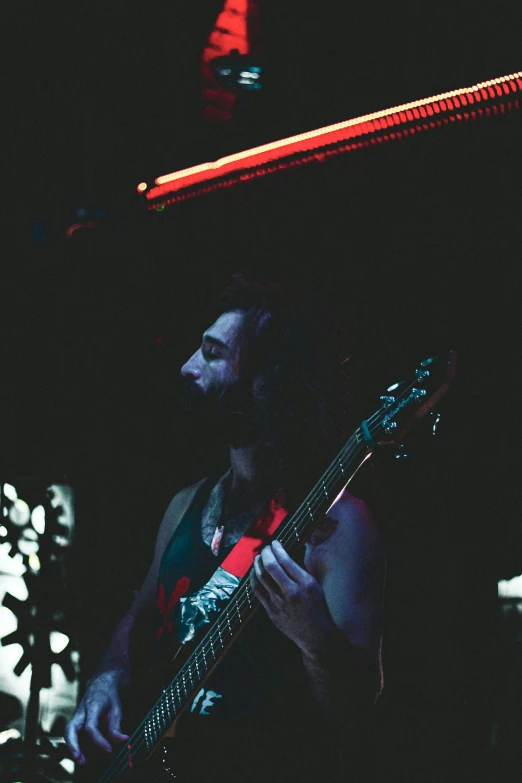 a man playing a guitar in a dark room, profile image, red scales, kailee mandel, vaughan bass