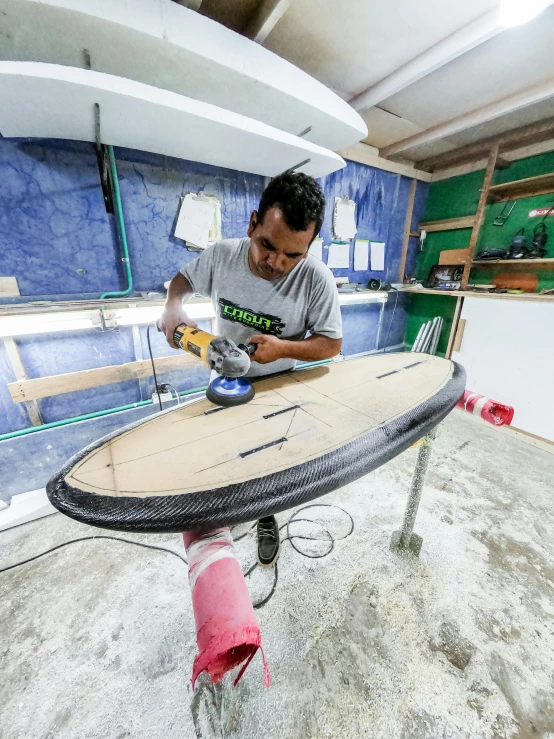 a man sanding a surfboard in a garage, zaha hadi, avatar image, profile image