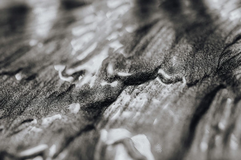 a black and white photo of a wet surface, a macro photograph, by Adam Marczyński, unsplash, lyrical abstraction, carved wood, wet fabric, blurred, shiny layered geological strata