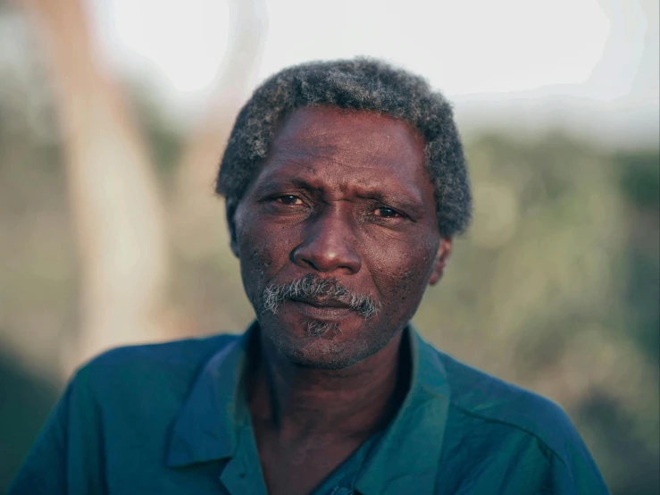 a close up of a person wearing a green shirt, by Peter Churcher, hurufiyya, 1990 photograph, obunga, dark grey haired man, posed