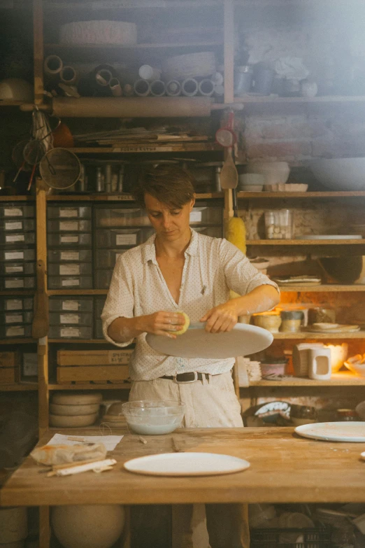 a man that is standing in front of a table, process art, glazed ceramic, pan and plates, aussie, woman