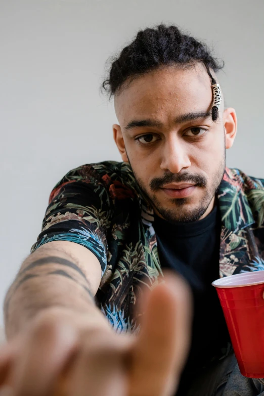 a man sitting at a table with a red cup, an album cover, trending on unsplash, antipodeans, giving the middle finger, mixed race, headshot portrait, official screenshot