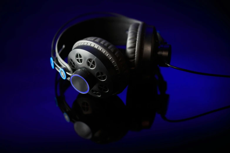 a pair of headphones sitting on top of a table, deep blue lighting, 8k studio photography, black, gears and lights