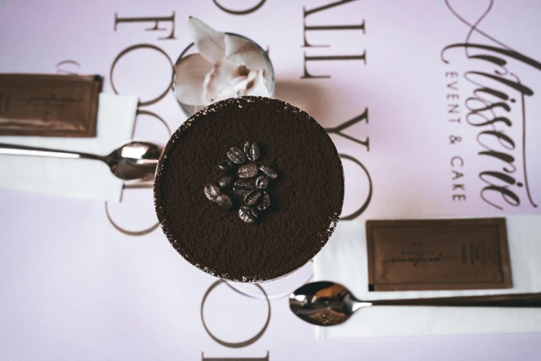 a chocolate cake sitting on top of a table, trending on unsplash, private press, cocktail in an engraved glass, viewed from above, candy treatments, long coffee brown hair