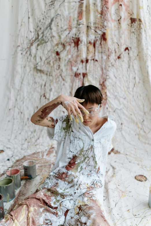 a woman sitting on a bed covered in paint, a painting, trending on pexels, action painting, ripped up white garment, ignant, in an apron covered in blood, su fu