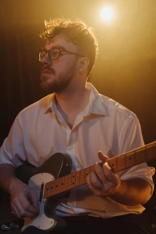 a man in a white shirt playing a guitar, an album cover, by Ryan Pancoast, unsplash, serial art, looking to his side, rubenesque, soft lights, bryan lee o'malley