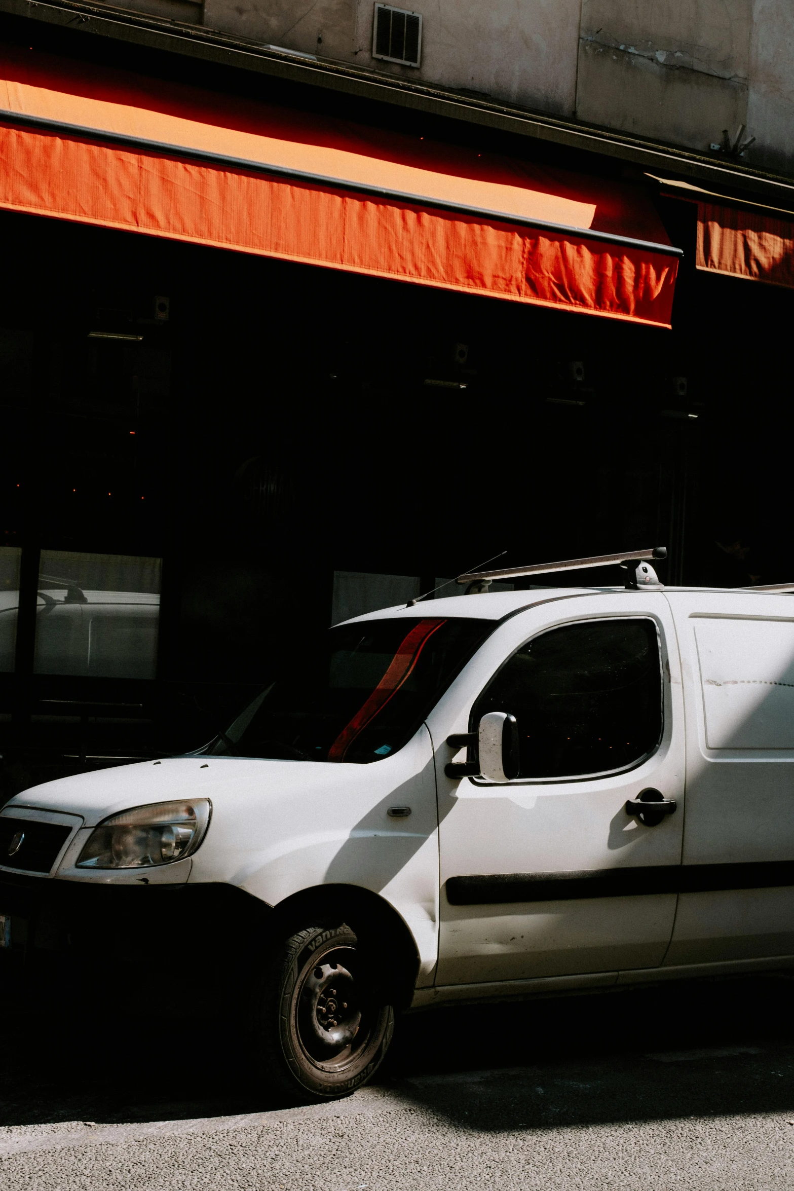 a white van parked in front of a building, unsplash, poor quality, orange and white, light source from the left, mechanic