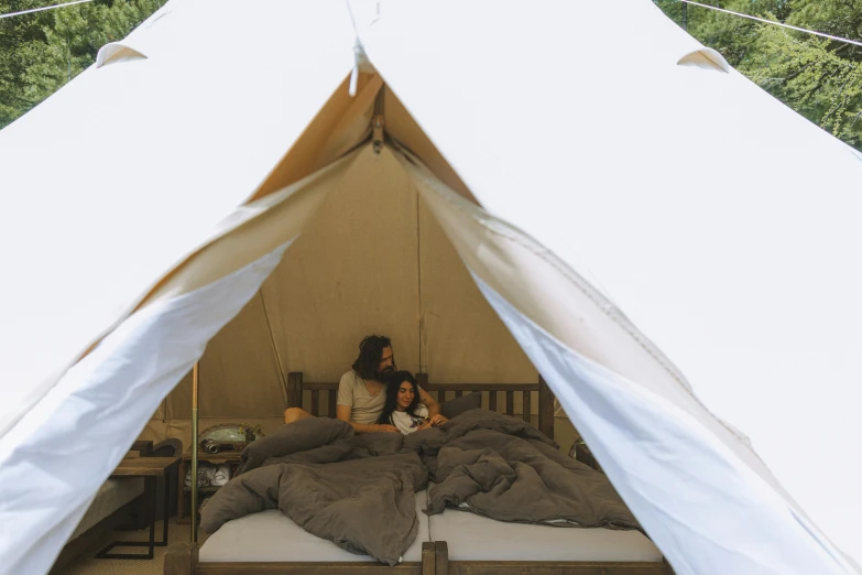 a couple of people sitting on top of a bed in a tent, unsplash, process art, glamping, manuka, grey, brown