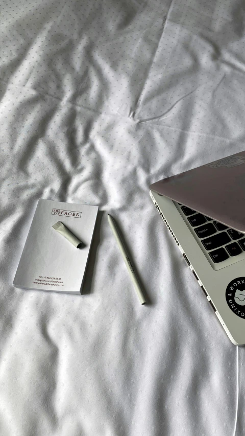 an open laptop computer sitting on top of a bed, by Robbie Trevino, pexels contest winner, chalk white skin, pencil, silver，ivory, instagram story