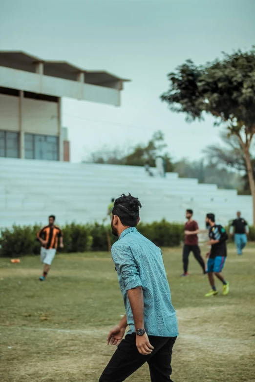 a group of young men playing a game of frisbee, pexels contest winner, happening, a portrait of rahul kohli, on a football field, long shot from the back, a handsome