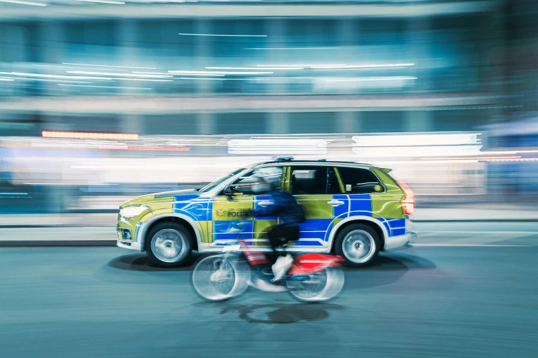 a vehicle driving down the street with a person on a bike