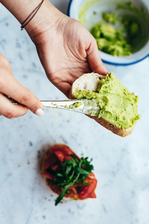 someone is eating guacamole off of some bread