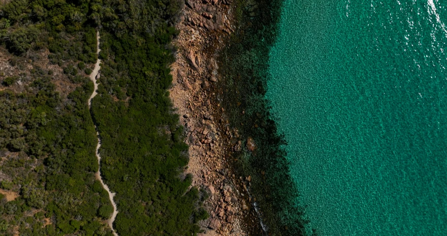 an aerial view of a large body of water, by Peter Churcher, pexels contest winner, rocky ground with a dirt path, the emerald coast, lachlan bailey, depth details