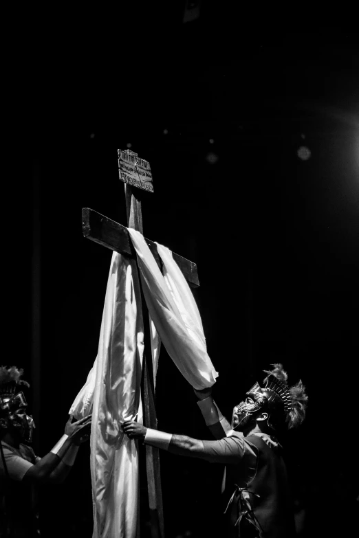 three men are around the cross during a performance