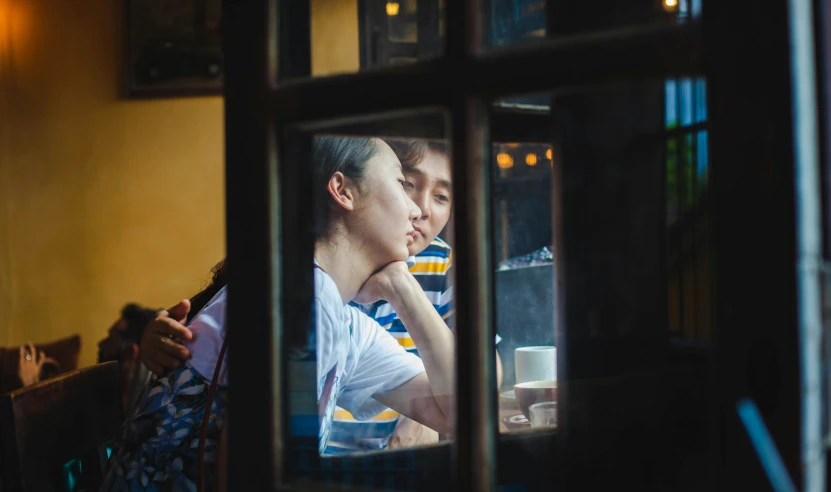 a man and a woman sitting at a table, a picture, pexels contest winner, happening, looking through a window frame, mingchen shen, embracing, wenjun lin