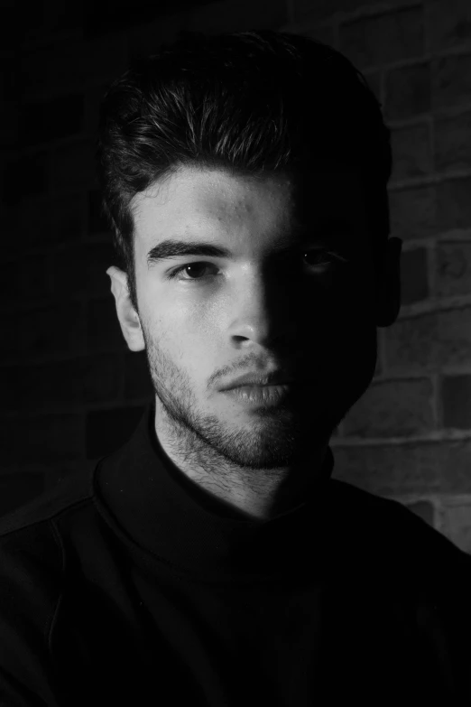 a man standing in front of a brick wall, a character portrait, inspired by Adrian Zingg, zayn malik, monochrome:-2, acting headshot, orelsan