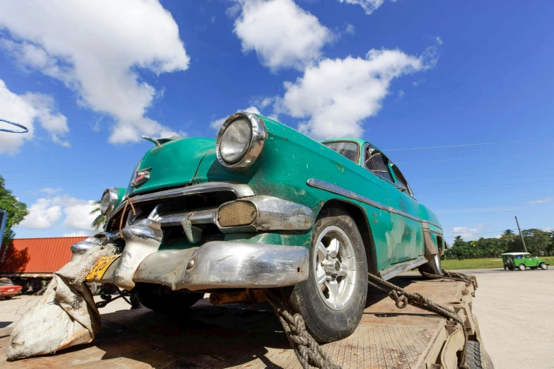 a green old car on top of a truck