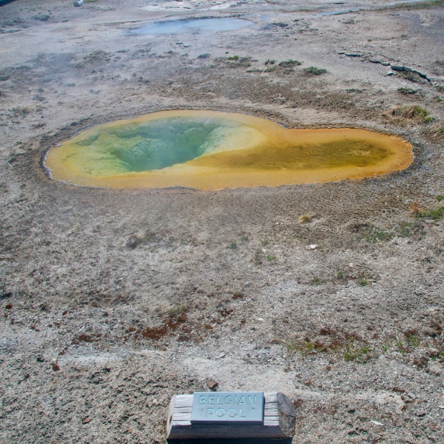 there is a gold colored pond surrounded by dirt