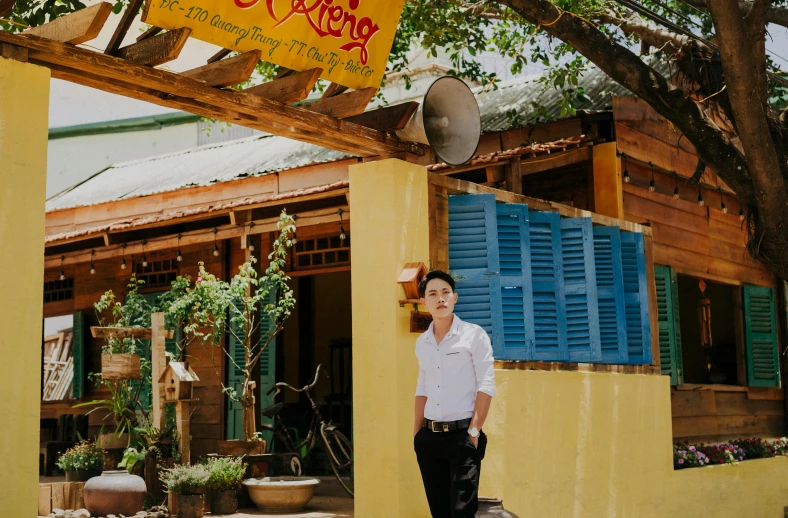 a man standing in front of a yellow building, restaurant exterior photography, do hoang tuong artwork, king, standing in a cantina