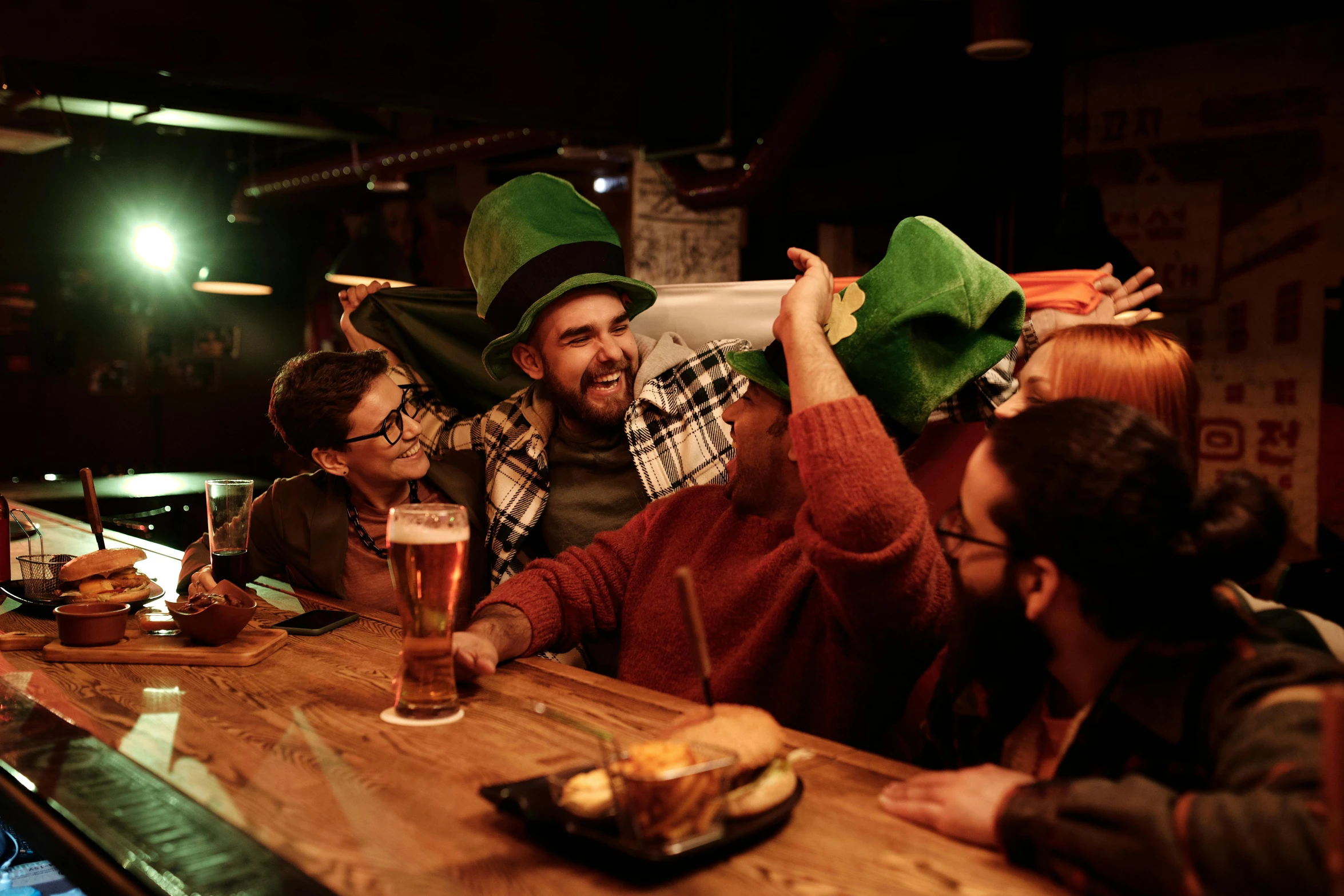 a group of people sitting around a wooden table, by Eamon Everall, pexels contest winner, wearing green tophat, drunkard, seasonal, square