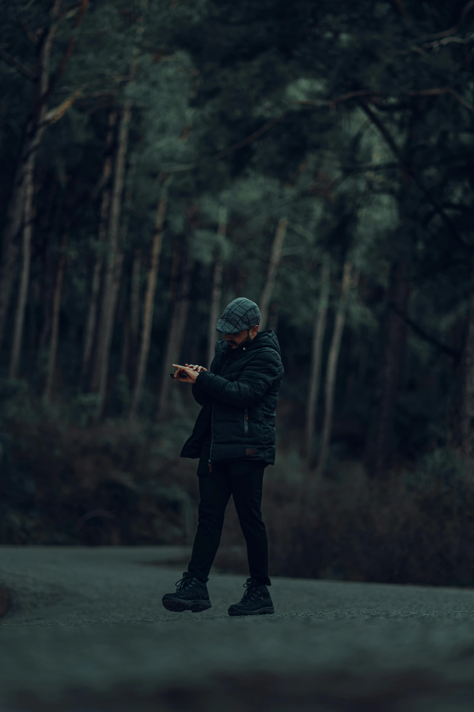 a person standing on a road looking at a cell phone, standing in a dark forest, man standing in defensive pose, streetwear, shot with sony alpha