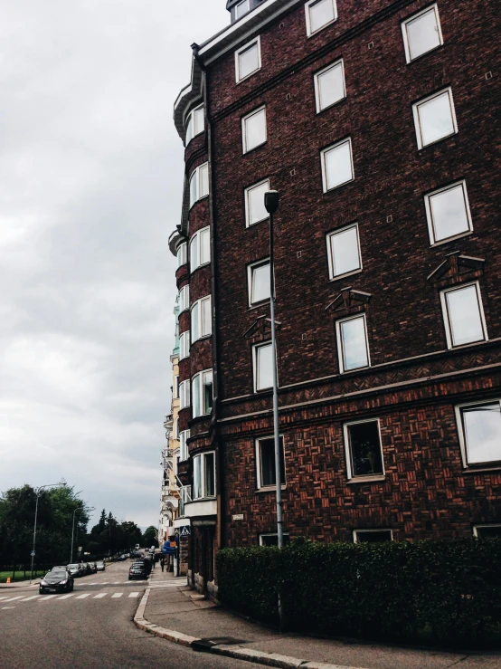 a tall brick building sitting on the side of a road, by Christen Dalsgaard, unsplash, helsinki, low quality photo, high details photo, multiple stories