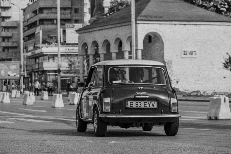 a black and white photo of a car driving down a street, a black and white photo, by Sven Erixson, mini cooper, rally driving photo, square, romanian