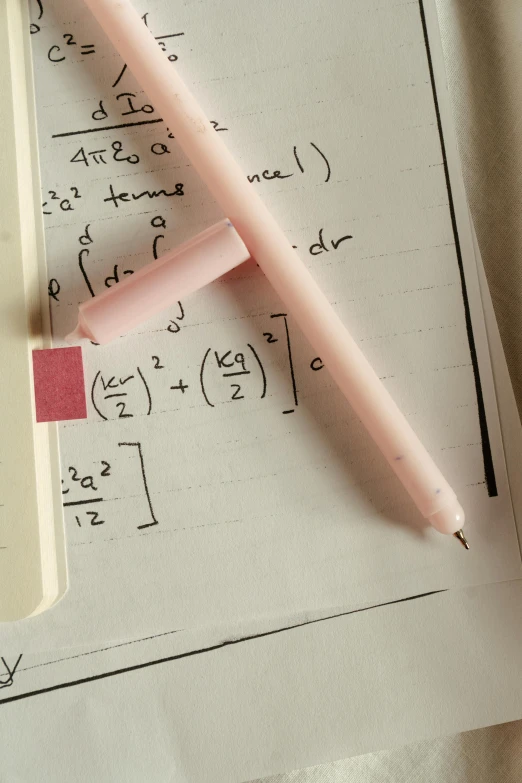 pink ballpoint pen and calculator resting on white paper