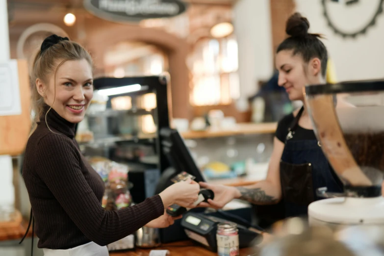 a couple of women standing next to each other at a counter, pexels, cash register, aussie baristas, avatar image, feature