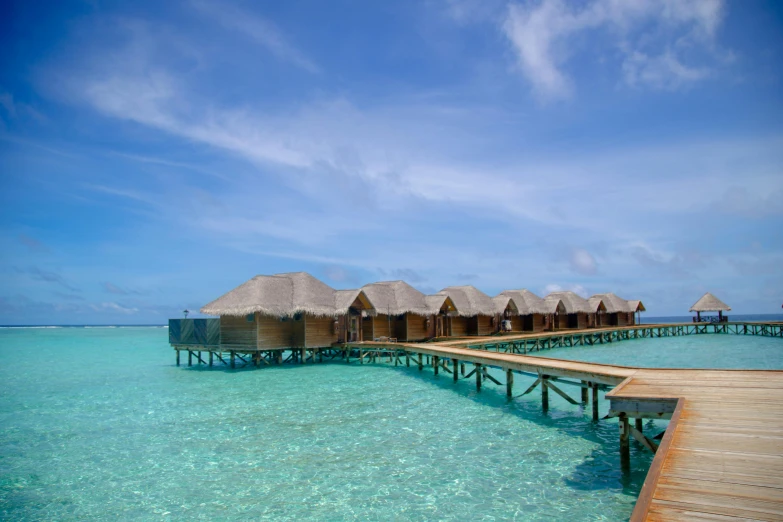 a long pier extending from the water towards some overwater huts