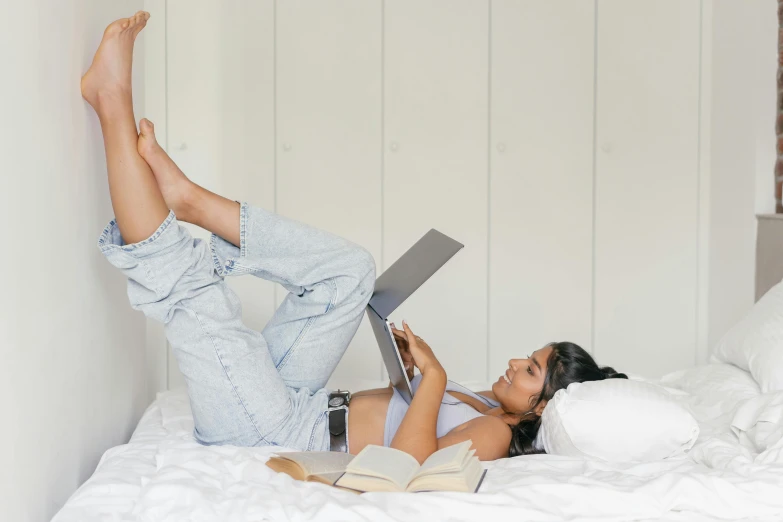 a woman laying on a bed reading a book, trending on pexels, figuration libre, wearing jeans, doing a sassy pose, computer aesthetic, full body photo