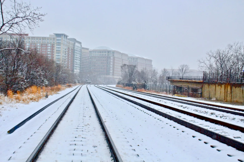 a train track covered in snow next to tall buildings, by Washington Allston, washington dc, fan favorite, skidding, misty