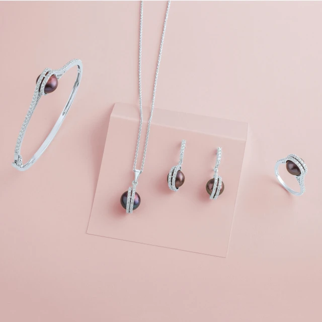 a collection of jewelry sitting on top of a pink surface, inspired by Perle Fine, in gunmetal grey, detailed product image, dim, overview